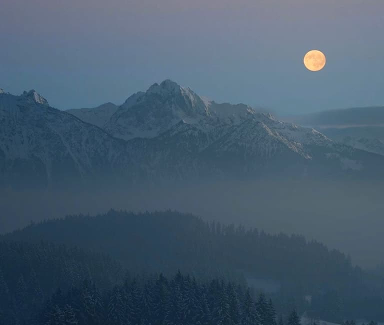 Moon over a mountain landscape at dusk